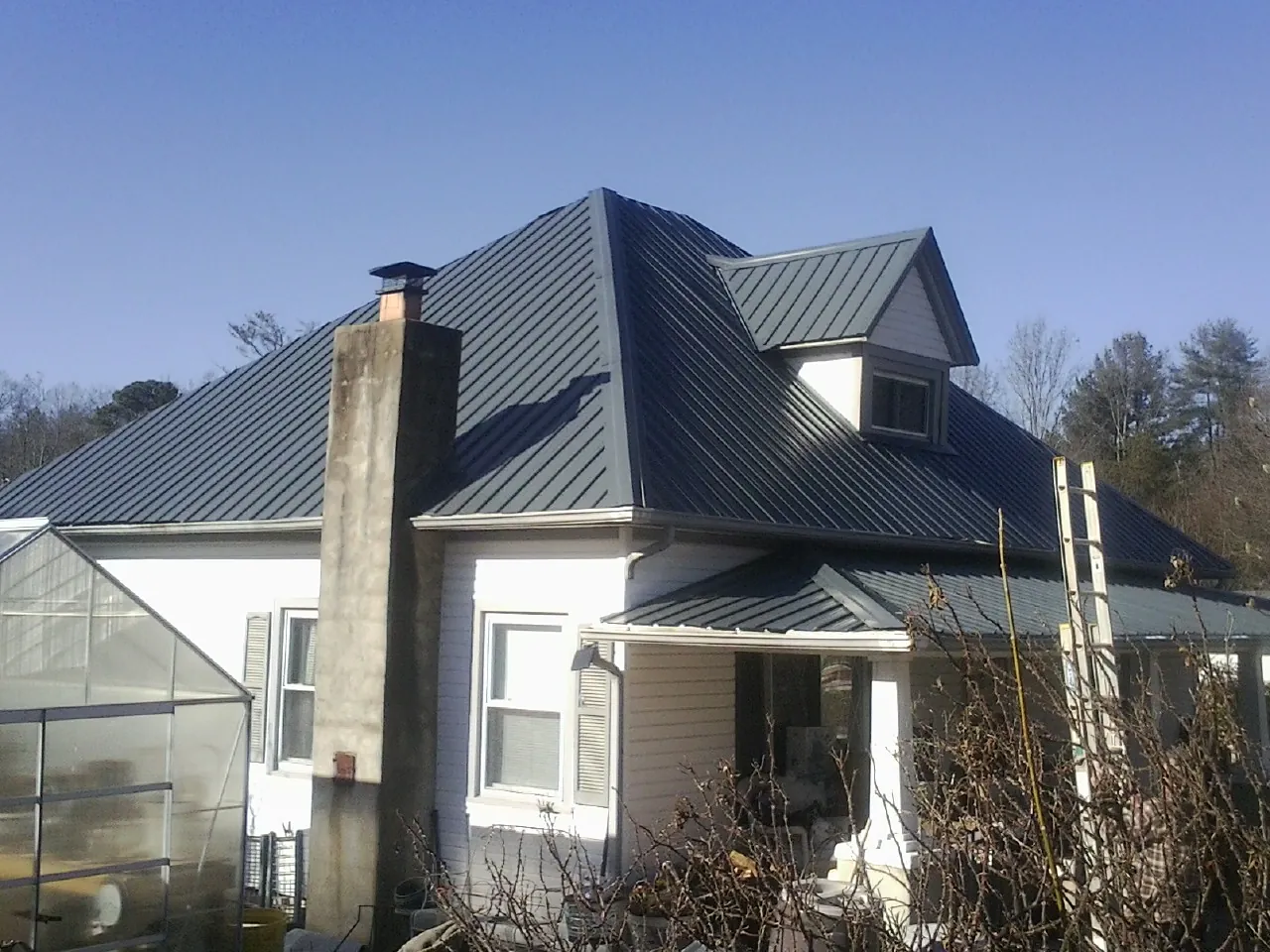 Dark blue standing seam metal roof on a white farmhouse with dormer — Slate & Tile Roof Repair by Roofing Brothers in Lititz