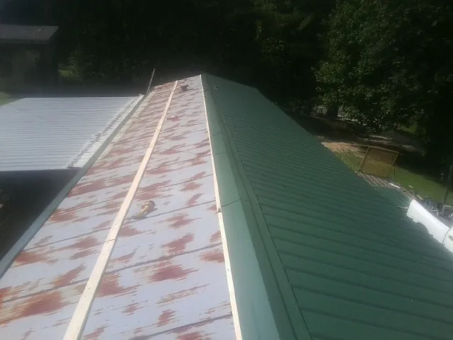 Old rusted panels beside newly installed green metal roofing — Wind Damage Roof Repair by Roofing Brothers in Lititz