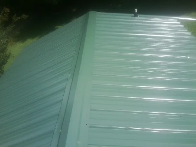 New green metal panels meeting at the ridge of a roof — Flat Roof Repair work by our crew in Lititz