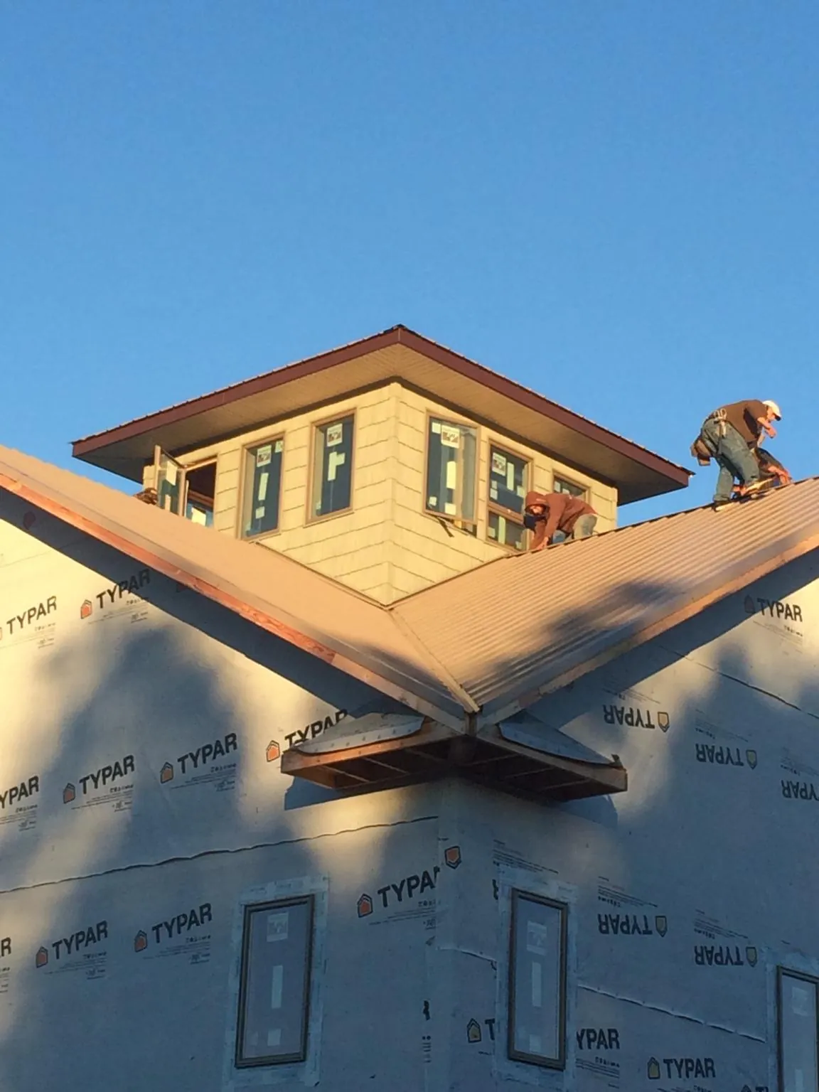 Roofers working around a rooftop cupola on a new metal roof at sunset — Roof Waterproofing in Lititz by Roofing Brothers